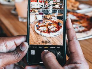 Cell phone taking a picture of pizza