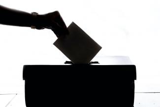 Silhouette of hand putting ballot in box