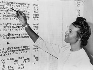 Shirley Chisholm looking at list of numbers posted on a wall