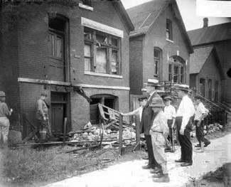 White men standing in front of vandalized house
