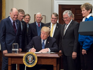 President Trump seated with advisors at White house signing of pardons