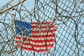 US Flag waving behind barbed wire