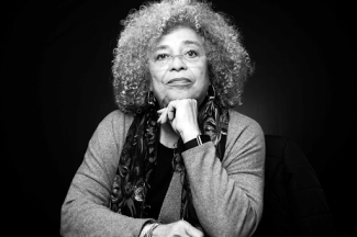 angela davis smiling with fist under chin sitting down