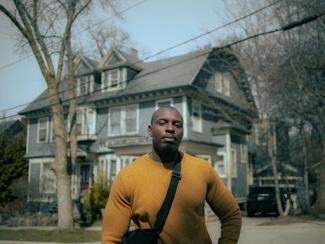 man in yellow crew neck long sleeve shirt standing near building in the daytime