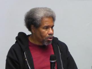 albert speaking at a university with black hoodie and red shirt on 