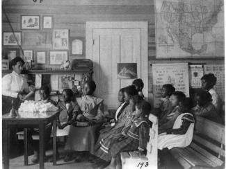black children and teacher in a classroom studying