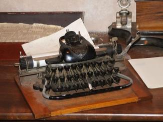 old fashioned type writer sitting on a wooden desk