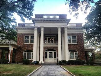 front of a house with columns and a manicured lawn