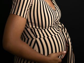 woman in black and white striped dress holding pregnant belly