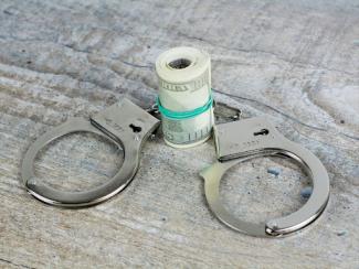 handcuffs around a roll of money on a table