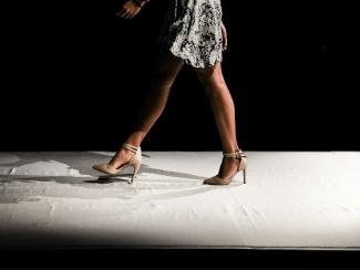 woman wearing black and white floral dress walking inside dark room