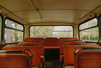 an empty bus with orange seats and. trees in the background