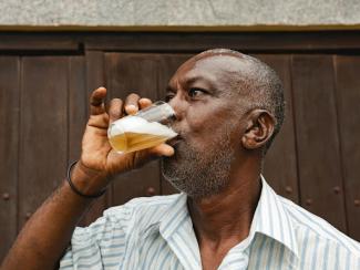 black man drinking beer in glass