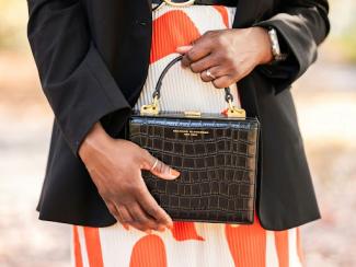 a woman in a dress holding a black purse