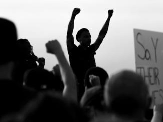 grayscale photo of people raising their hands