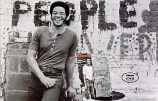 bill withers leaning against a wall and smiling