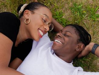 two black people laying down on the grass smiling