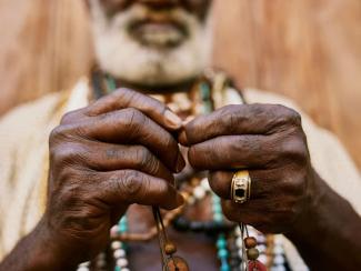 man with white beard holding a beaded necklace
