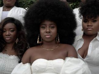 black women standing together wearing white tops