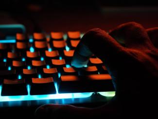 persons hand on blue lighted computer keyboard 