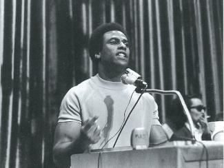 huey newton speaking in front of a podium