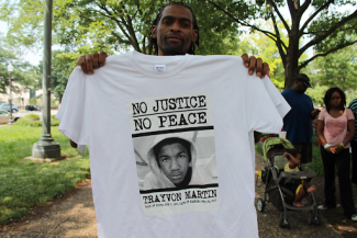 man holding no justice no peace shirt with trayvon martin face on the front