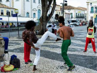 a group of people that are standing in the street and two people are engaging in street fighting