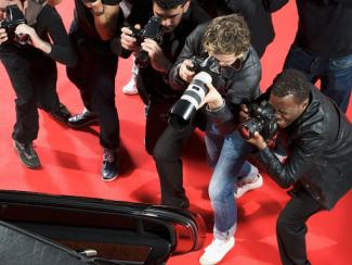 a group of photographers taking pictures of a man on red carpet 