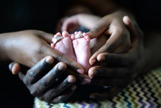 black parents holding little child's feet