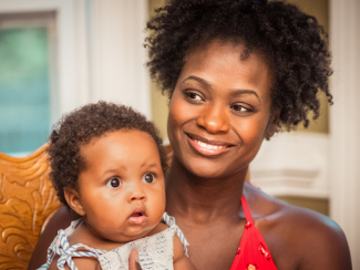 black woman smiling holding her baby 
