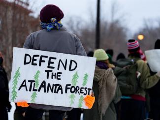 protestor holding sign that says defend the atlanta forrest
