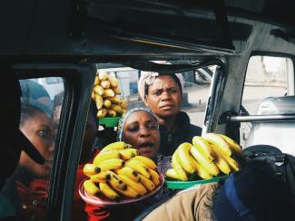 person stnading near vehicle holding banana