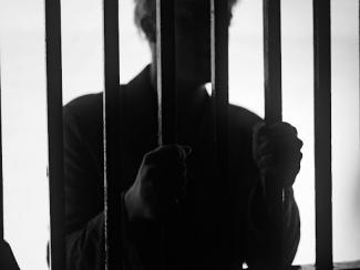 a man standing behind bars in a jail cell
