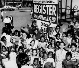 group of black people in front of a sign that says register to vote