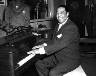 duke ellington sitting in front of a piano getting ready to play