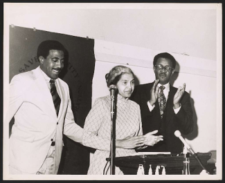 rosa parks standing at a podium with two gentleman