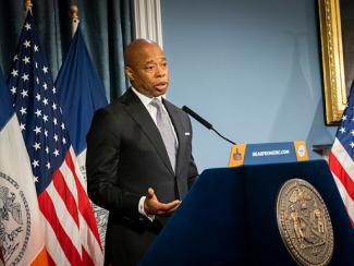 mayor adams speaking in front of a podium