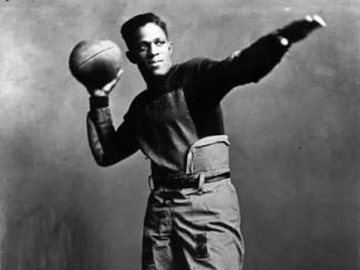 fritz pollard with a football in hand