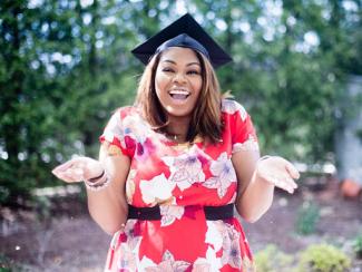 black woman smiling with graduation cap on