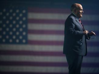 rudy giuliani standing with american flag in the background