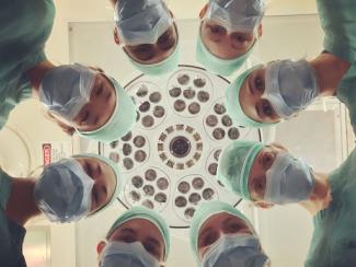 team of surgeons looking down with an operating room light ahead