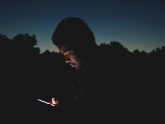 person looking down at phone in the dark