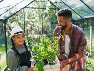 young brother with sister working outdoors in backyard greenhouse