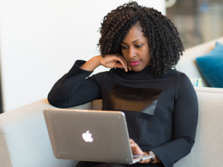 black woman sitting in front of a laptop 
