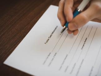 a person signing paperwork on a table