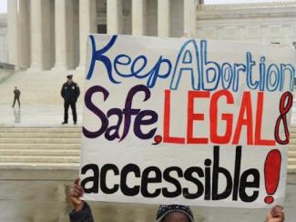 sign being held up that says keep abortion safe, legal and accessible