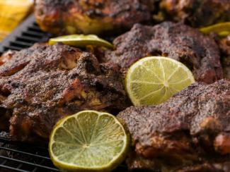 a close up of a grill with meat and lemons 