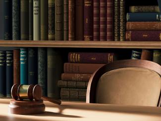 judges gavel on a table in front of a bookshelf