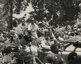 Crowds cheer Mr. Julius Nyerere as he drives through the cit on "Madaraka Day", i.e. Responsible Government Day. On his right is his sister, on his left Mrs. T. Mohamed and Mr. John Rupia, Vice-President of Tanu.