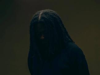 a man with dreadlocks standing in a dark room